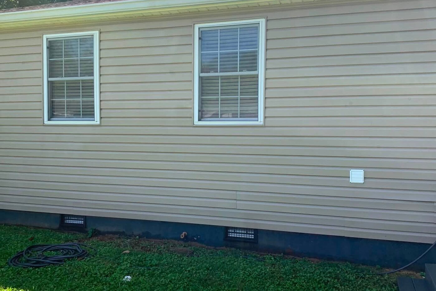The same wall after a soft wash, the siding bright and the foundation clean