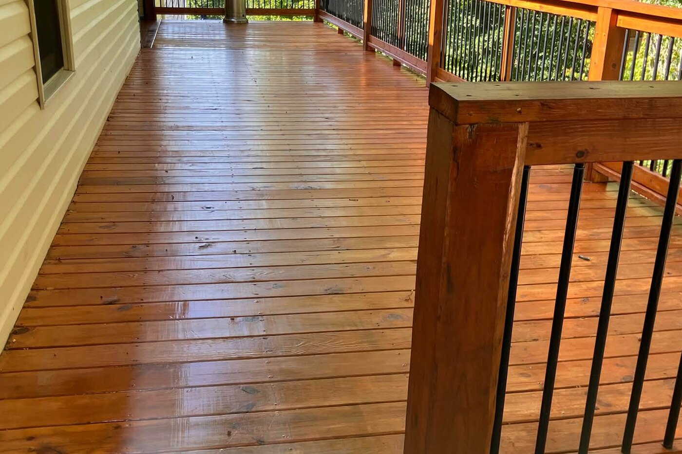 The same deck restored, the boards rich and warm with the wood grain showing again