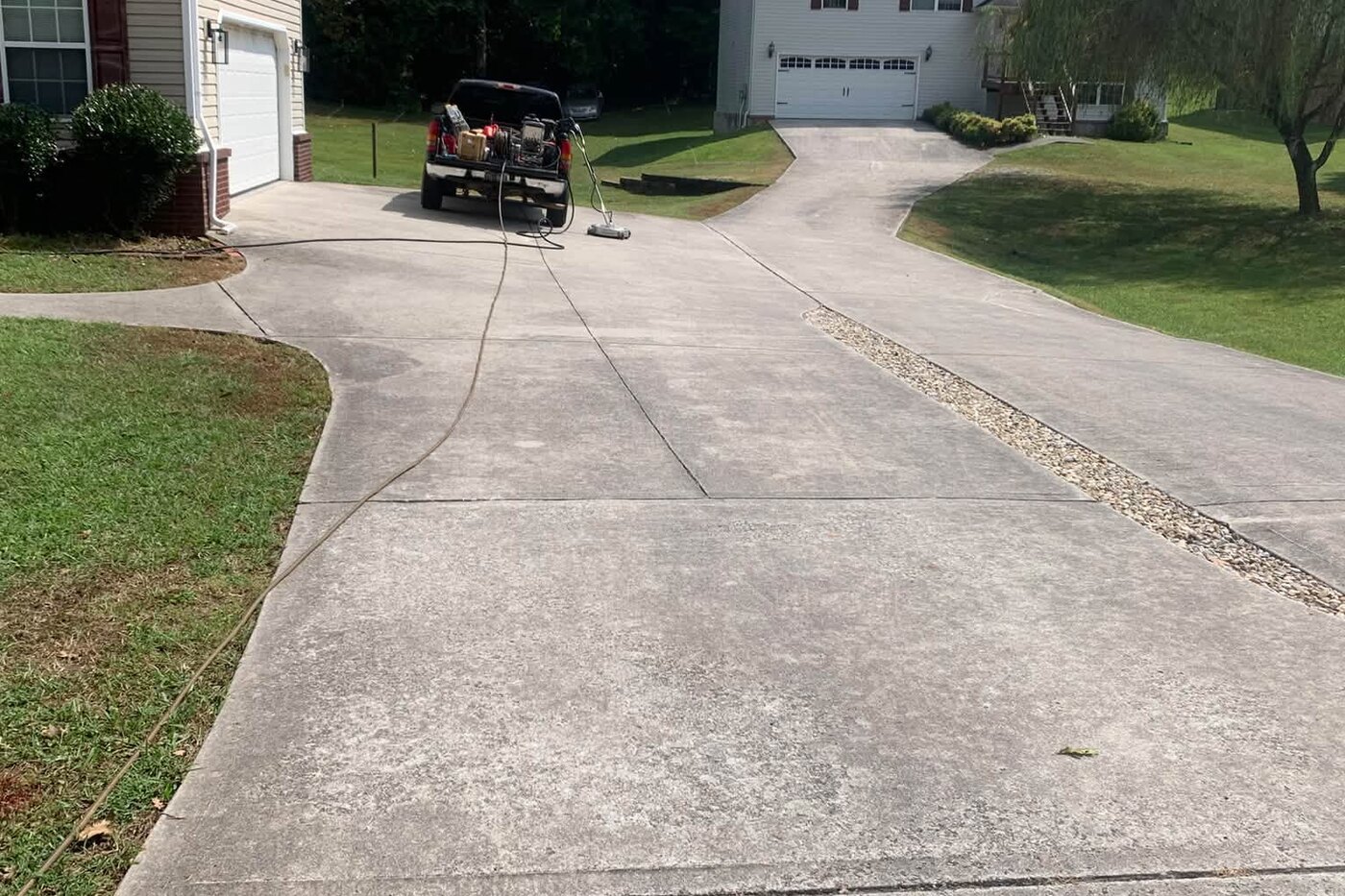 A long concrete driveway dulled grey and green with years of dirt before cleaning