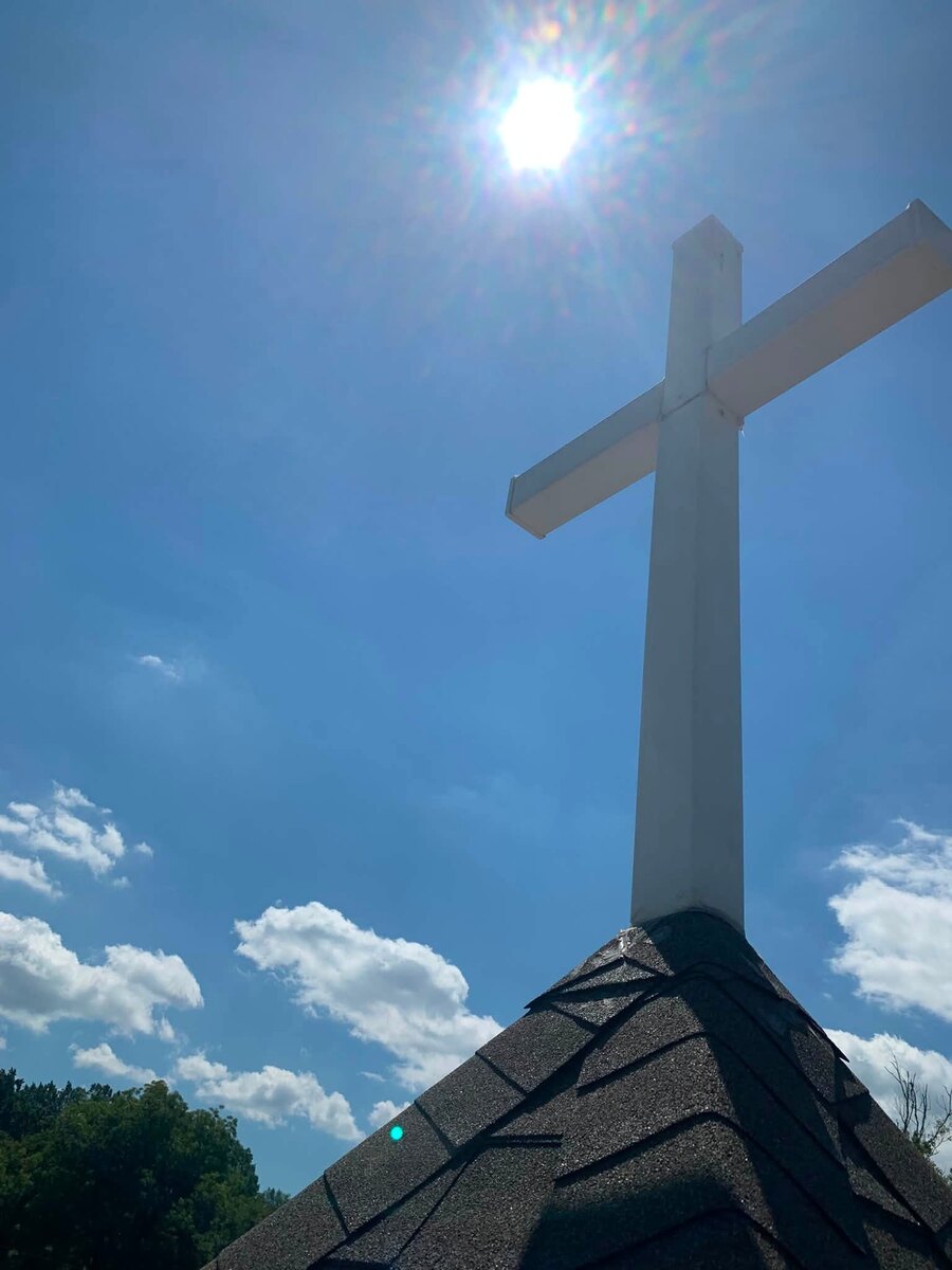 A steeple cross washed clean and bright against a blue sky