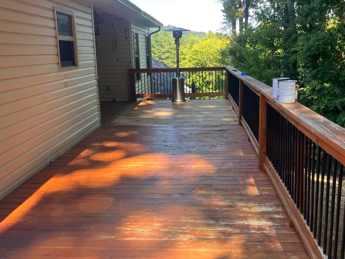 A long wooden deck after restoration, the boards rich and warm with the grain showing and the rail posts clean